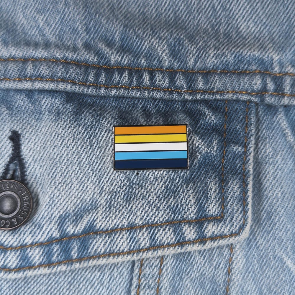 Close up image of an aroace pin on a denim jacket pocket
