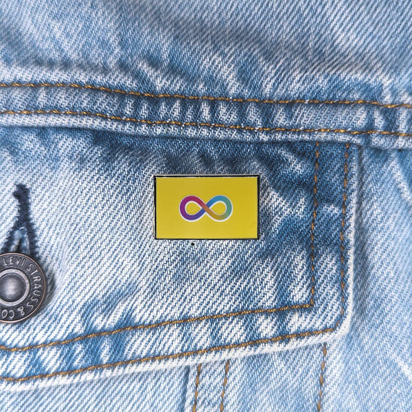Close up image of an autistic pride pin on a denim jacket pocket