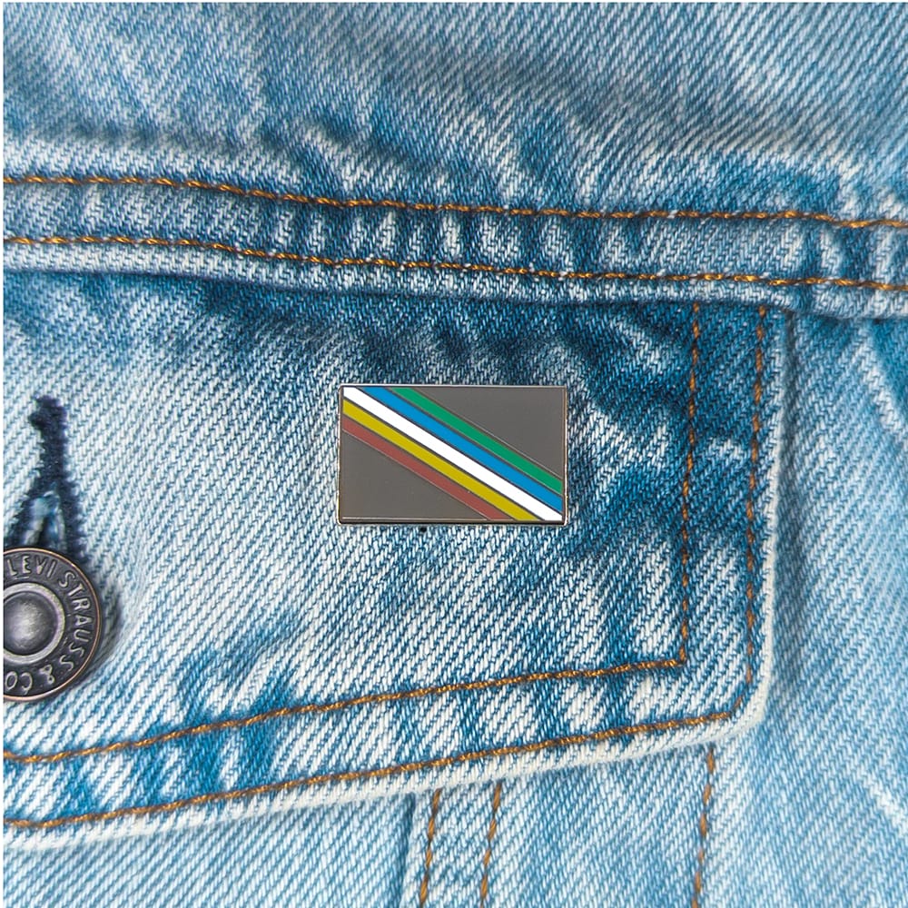 An image of a disability pride pin on a denim jacket pocket