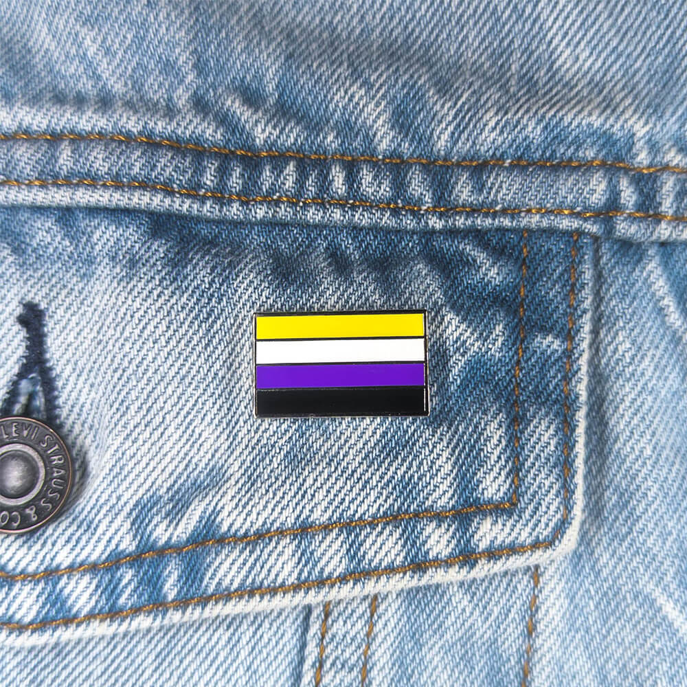 An image of a non-binary pin on a denim jacket pocket