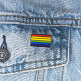 An image of a rainbow pin on a denim jacket pocket