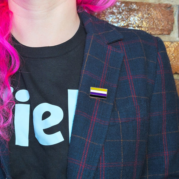 A non-binary pin on the lapel of a woman