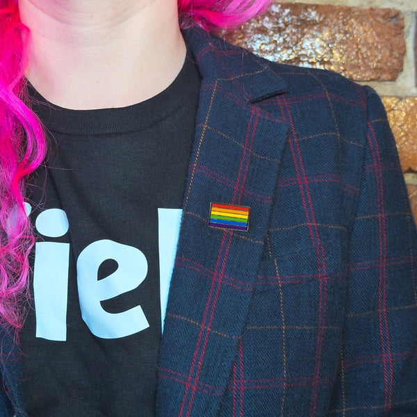 A rainbow pin on the lapel of a woman